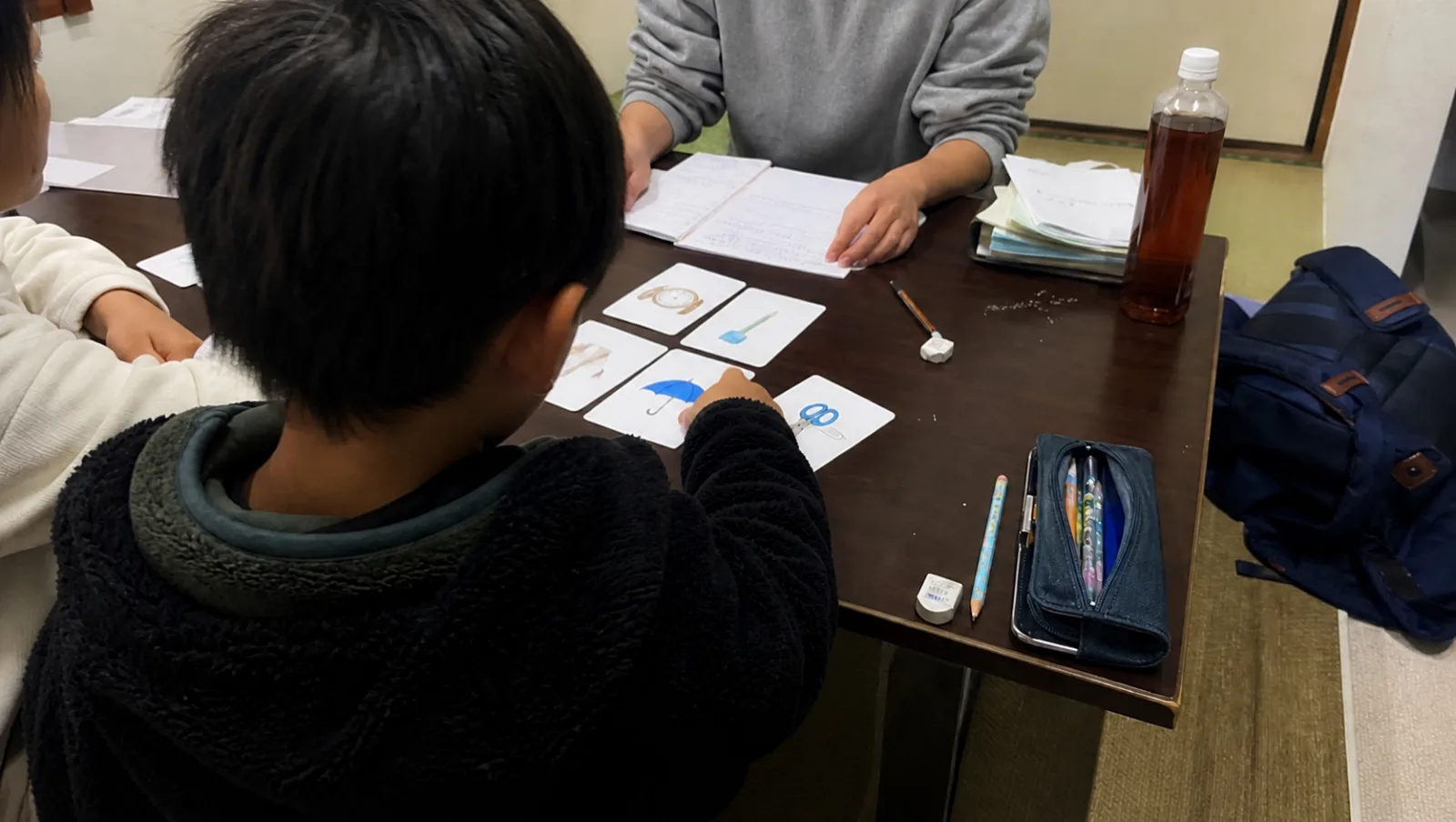 生活に身近な絵カードとノートを囲んで日本語を学ぶ活動イメージ